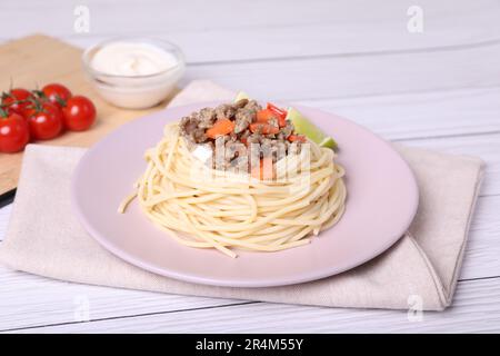 Leckeres Hackfleisch mit Spaghetti und Gemüse auf einem weißen Holztisch Stockfoto