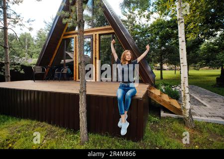 Frau in einem Landhaus sitzt auf der Terrasse und genießt eine schöne Aussicht und frische Luft Stockfoto