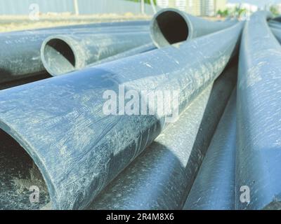 Bau eines Kanalisationssystems in einem neuen Mikrobezirk. Schwarze Gummirohre liegen auf dem Sand der Baustelle. Abflusssystem. Rohre sind ein Scra Stockfoto