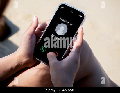 Eingehender Anruf mit unbekanntem Anrufer, böswilliges Anrufkonzept. Unbekannte Nummer wird auf dem Smartphone in der Hand der Frau am Urlaubstag um angezeigt Stockfoto