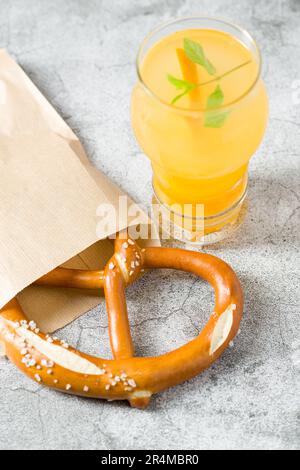 Brezel in Geschenkpapier eingewickelt mit einem Getränk daneben auf einem Steintisch Stockfoto