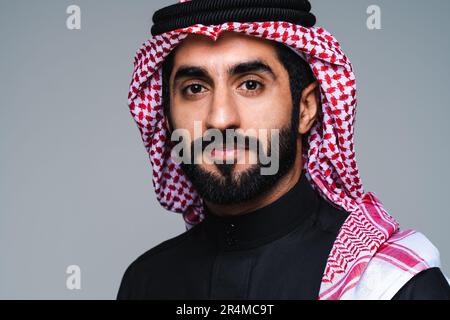 Attraktiver arabischer Saudi-arabischer Mann aus dem Nahen Osten mit traditioneller saudi-Kleidung im Studio - arabisch-muslimischer erwachsener Geschäftsmann mit tollem Porträt Stockfoto