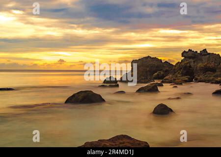 Strandlandschaft mit Felsformationen während des Sonnenaufgangs am Sumurtiga Beach, Sabang, Aceh, Indonesien. Stockfoto