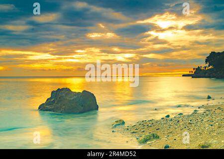 Strandlandschaft mit Felsformationen während des Sonnenaufgangs am Sumurtiga Beach, Sabang, Aceh, Indonesien. Stockfoto