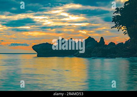 Strandlandschaft mit Felsformationen während des Sonnenaufgangs am Sumurtiga Beach, Sabang, Aceh, Indonesien. Stockfoto