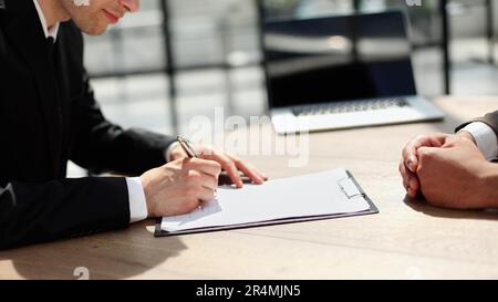 Geschäftsmann, der mit Stift eine Vertragsunterzeichnung für ein Anlagemitteldokument auf dem Tisch unterschreibt. Stockfoto