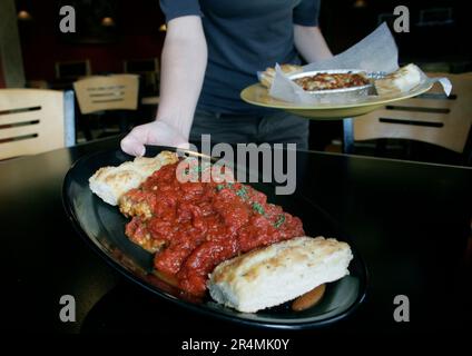 Eine Kellnerin serviert den Gästen an einem Tisch in einem italienischen Restaurant in Nashville, Tennessee, Speisen. Stockfoto