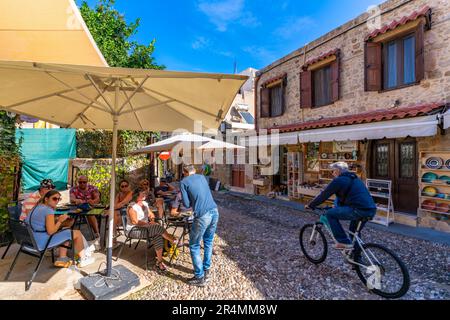 Blick auf Café und Radfahrer auf Kopfsteinpflaster, Altstadt von Rhodos, UNESCO-Weltkulturerbe, Rhodos, Dodekanes, griechische Inseln, Griechenland, Europa Stockfoto