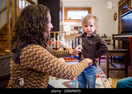 Eine Mutter hilft ihrem kleinen Kind beim Anziehen Stockfoto