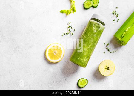Grüner Smoothie in Kunststoffflasche und Zutaten auf weißem Hintergrund, Draufsicht, Kopierbereich. Frischer, roher Detox Smoothie oder grüner Saft für gesunde Ernährung Stockfoto