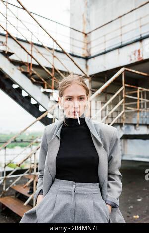 Eine Frau mit einer Zigarette steht neben der Treppe Stockfoto
