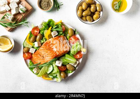 Gegrilltes Lachsfilet und frischer Gemüsesalat mit Tomaten, Oliven, Salat und Fetakäse. Mediterrane Küche - griechischer Salat und gerösteter Lachs, t Stockfoto