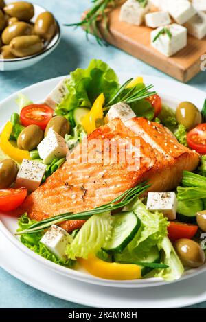 Gegrilltes Lachsfilet und frischer Gemüsesalat mit Tomaten, Oliven, Salat und Fetakäse. Mediterrane Küche - griechischer Salat und gerösteter salm Stockfoto