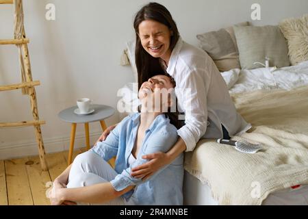 Zwei junge Frauen, die zu Hause zusammen sitzen und lachen Stockfoto