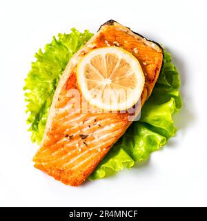 Gegrilltes Lachssteak isoliert auf weißem Hintergrund. Gerösteter Lachs auf Salatblatt - gesunde Keto-Lebensmittelzutat. Stockfoto