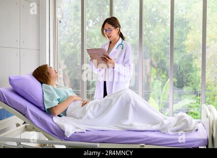 Asiatischer Arzt im Spitalgespräch mit dem Patienten Stockfoto