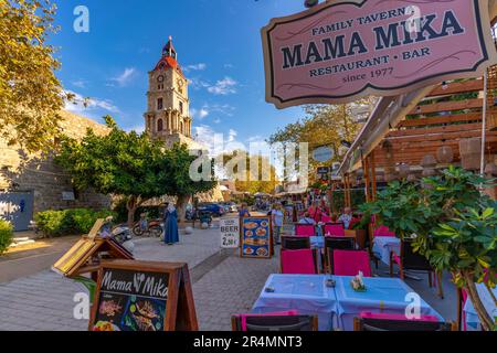 Blick auf den mittelalterlichen Uhrenturm und Restauranttische, die Altstadt von Rhodos, UNESCO-Weltkulturerbe, Rhodos, Dodekanes, griechische Inseln, Griechenland, Europa Stockfoto