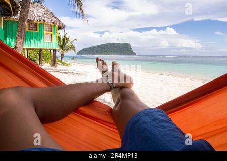 Männerbeine auf Hängematte am tropischen Sandstrand von Samoa Stockfoto