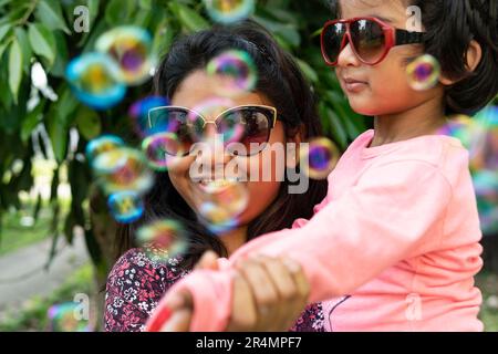 Schwestern machen Spaß mit Seifenblasen im Freien Stockfoto