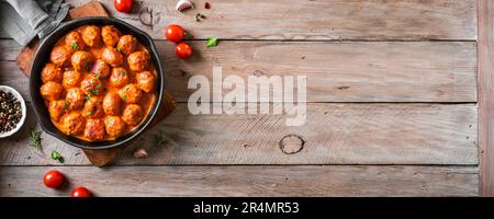 Hausgemachte Fleischbällchen in Tomatensauce, Draufsicht, Kopierbereich. Gebratene Fleischbällchen mit Rindfleisch in einer Gusseisenschale auf Holzhintergrund, Banner. Stockfoto