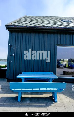 Olberg; Olbergstranden; Raege; Norwegen; Mai 20 2023; Traditionelles Blaues Gebäude Mit Holztisch Und Sitzbank Ohne Personen Stockfoto