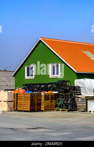 Olberg; Olbergstranden; Raege; Norwegen; Mai 20 2023; Traditionelles Grün gemaltetes Haus mit Hummer und Krabbenbechern, die vor Einem klaren blauen Sk gestapelt sind Stockfoto