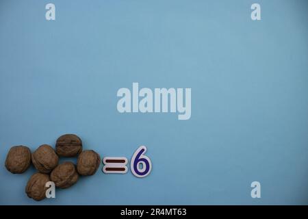 Sechs Walnüsse in Schale, von oben fotografiert, auf dem Rand eines blauen Hintergrunds platziert. Stockfoto