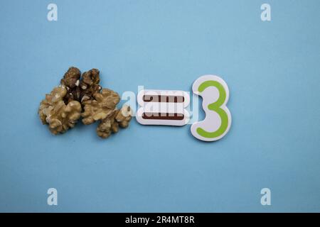 Drei Walnusskerne, fotografiert von oben, auf blauem Hintergrund. Stockfoto