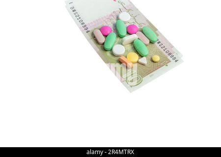 Pillen mit Pakistan zehn Rupien-Noten isoliert auf weißem Hintergrund. Das Kostenkaufskonzept für Arzneimittel. Stockfoto