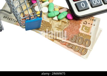 Medizinpillen mit Mini-Wagen und Taschenrechner auf einem pakistanischen 5000-Banknoten auf weißem isoliertem Hintergrund. Das Kosten- und Kostenkonzept der Medizin. Stockfoto