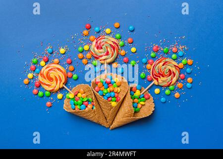 Waffelkonus voller traditioneller Süßigkeiten, die auf farbigen Hintergrund fallen, mit Platz für Kopien. Frohes Weihnachtsangebot. Stockfoto