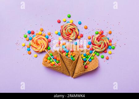 Waffelkonus voller traditioneller Süßigkeiten, die auf farbigen Hintergrund fallen, mit Platz für Kopien. Frohes Weihnachtsangebot. Stockfoto