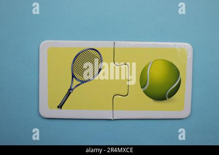 Puzzles auf blauem Hintergrund überlagern. Tennisschläger und Ball von oben fotografiert. Stockfoto