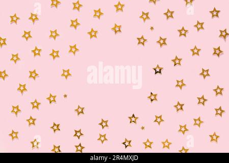 Konfetti mit goldenen Sternen auf pinkfarbenem Hintergrund und rundem Kopierfeld. Goldene glitzernde Textur. Neujahrsfeiertage im Hintergrund. Hochzeitstag, Geburtstag. Grüß Dich Stockfoto
