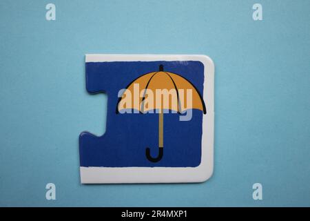 Puzzles auf blauem Hintergrund überlagern. Orangefarbener Regenschirm, von oben fotografiert. Stockfoto Puzzles auf blauem Hintergrund überlagern. Orangefarbener Regenschirm, von oben fotografiert. Stockfoto