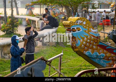 Ein Paar hält brennende Räucherstäbchen und betet und segnet vor einem festgemachten Drachenboot auf dem Parfüm River in Hue, Vietnam. Stockfoto