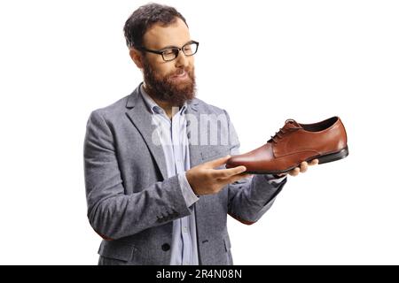 Ein bärtiger Mann, der einen braunen Lederschuh auf weißem Hintergrund sieht Stockfoto