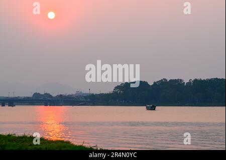Der Sonnenuntergang über dem Parfüm River und ein Drachenboot an einem milden Abend in Hue, Vietnam. Stockfoto