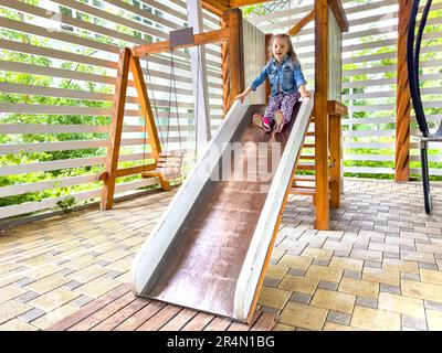 Das Kind steigt von der Kinderrutsche ab. Stockfoto