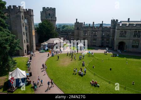 Besucher, die sich im zentralen Innenhof des aus dem 12. Jahrhundert erbauten Warwick Castle in Warwick, Warwickshire, Großbritannien, umsehen Stockfoto