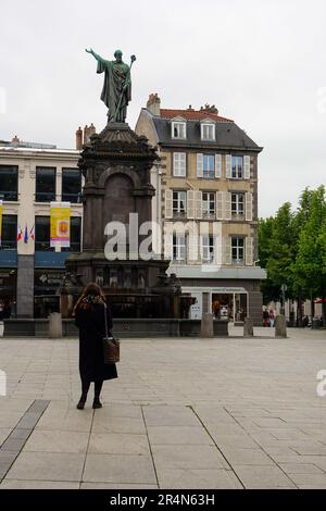 Stilvoll gekleidete junge Frau, die an der Statue von Papst Urban II in Pl. vorbeikommt. De la Victoire, Auvergne, Clermont-Ferrand. Stockfoto