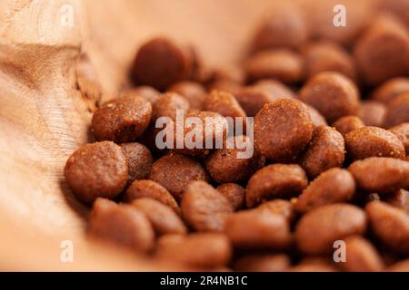 Katzenfutter in ökologischer Holzschüssel. Nahrhaftes knuspriges braunes Futter für Kätzchen. Makroaufnahme Stockfoto