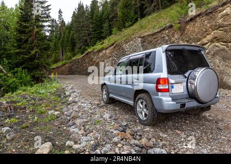 Geländewagen im Geländewagen auf einer schmalen Schotterstraße zum Zekari Pass (Meskheti Range), Georgia, üppiger kaukasischer Nadelwald um sich herum. Stockfoto