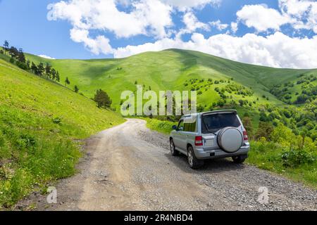 Fahrt im Geländewagen auf der M-20, gewundene Schotterstraße in Richtung Tskhratskaro Pass, Georgia mit Trialeti (Kaukasus)-Bergen und grünem Grasland. Stockfoto