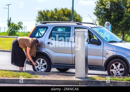 Junge Frau, die den Reifendruck auf dem Garagenplatz prüft - Loches, Indre-et-Loire (37), Frankreich. Stockfoto