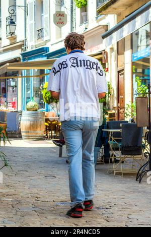 Junger Mann im „Los Angeles“-T-Shirt beim Spaziergang entlang der Straße - Loches, Indre-et-Loire (37), Frankreich. Stockfoto