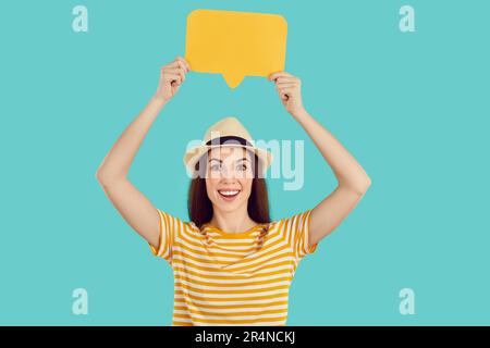 Fröhliche junge Weiße, die im türkisfarbenen Studio eine dialogebase über dem Kopf aufzieht Stockfoto