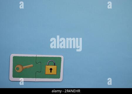 Puzzles auf dem blauen Hintergrund platzieren. Schlüssel und Schloss. Stockfoto