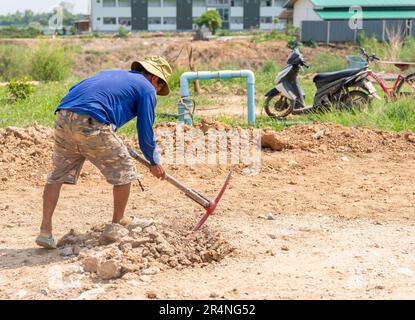 Arbeiter gräbt mit Spitzhacke, um den Boden vor dem Gießen von Beton einzustellen. Stockfoto