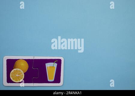 Informationspuzzles am Rand des blauen Hintergrunds. Saft und Orangenscheiben in einem Glas. Stockfoto